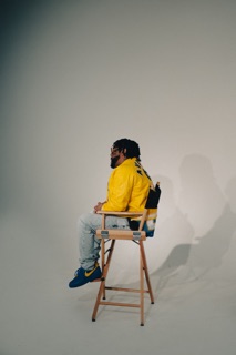 Artist seated on a director's chair in a white cyc studio