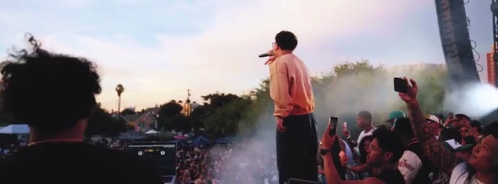 Performer on stage with a mic, crowd filming